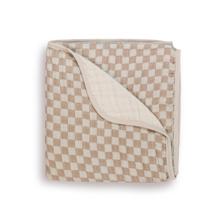 Folded muslin baby blanket with taupe and cream checkerboard pattern, showing cream reverse side