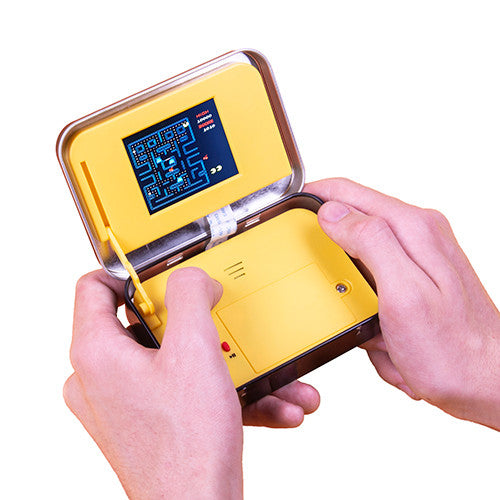 Hands holding open PAC-MAN Arcade In A Tin portable handheld game displaying PAC-MAN gameplay screen
