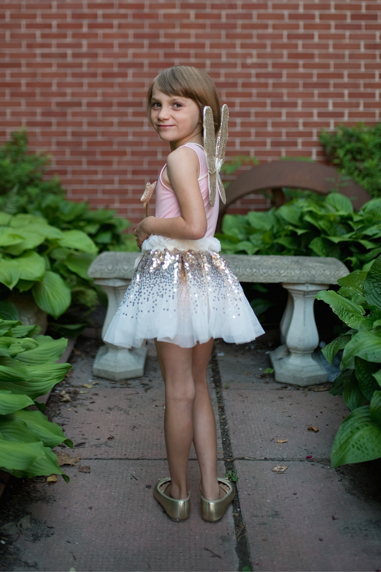 Child wearing gold sequin tutu skirt with fairy wings and wand costume set