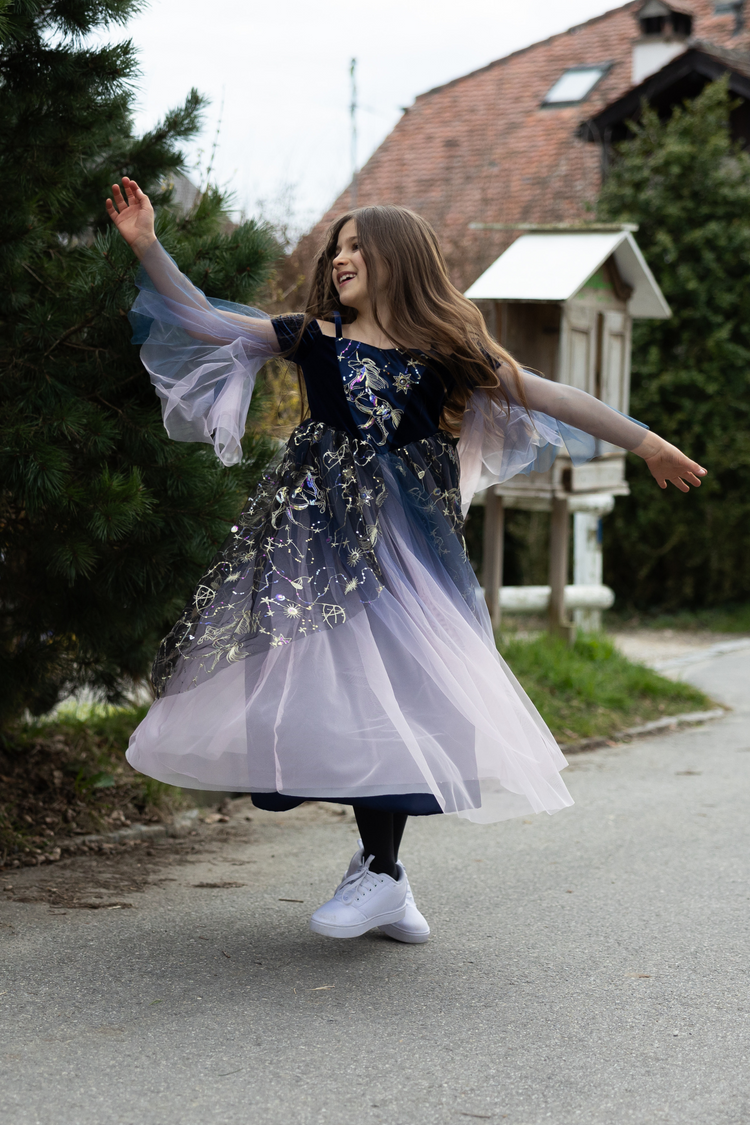 Child twirling in navy and lavender tulle Twilight Enchantress Gown with gold constellation details