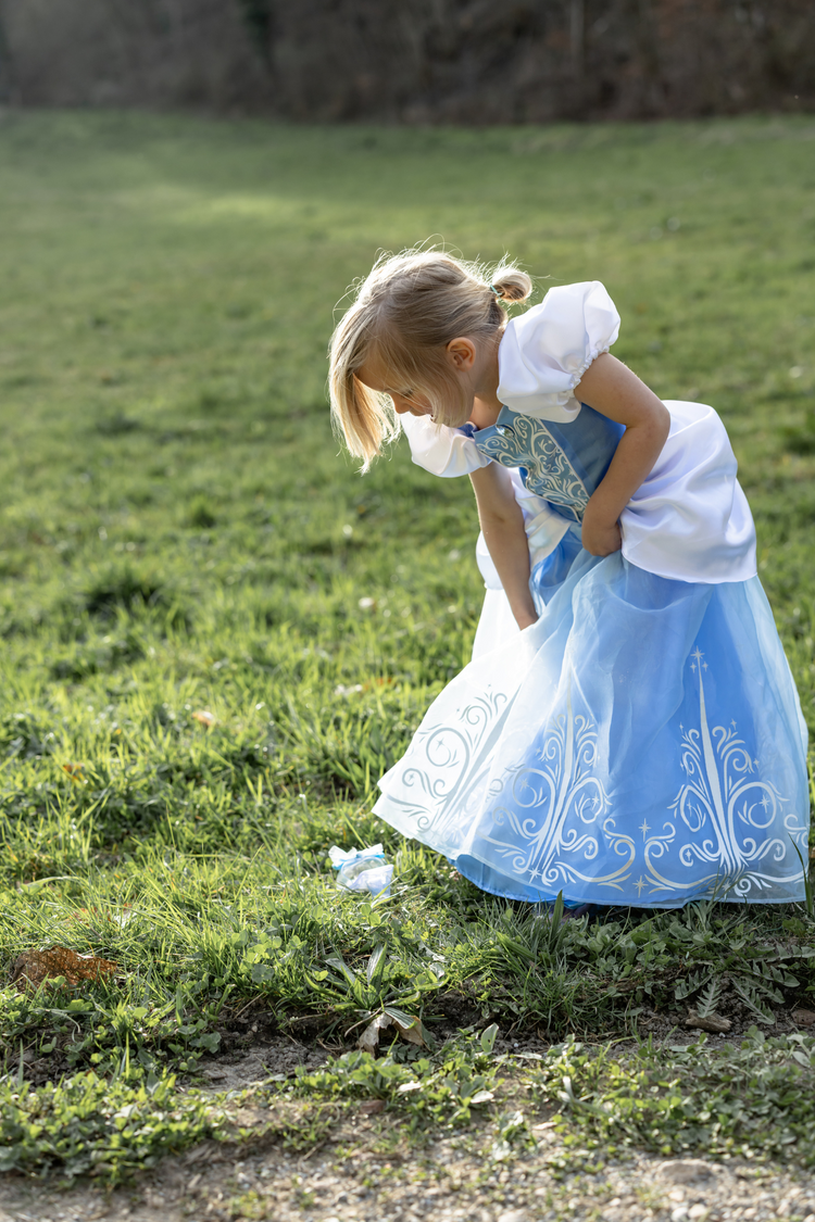 Young girl wearing Cinderella princess dress in light blue and white outdoors