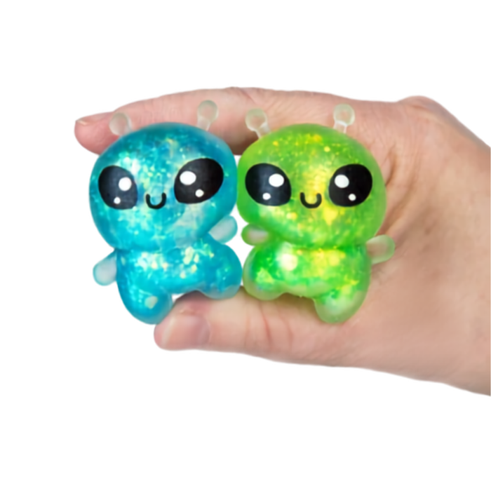 Hand holding two sparkly alien squeeze toys in blue and green glitter colors