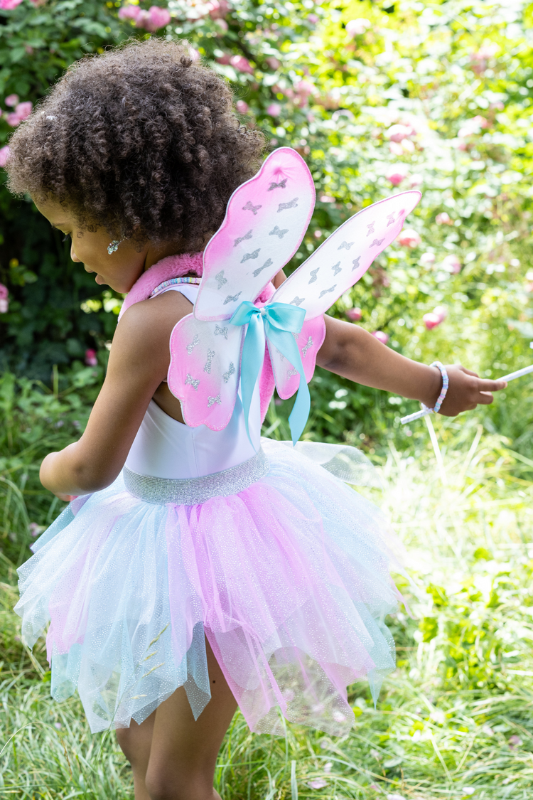 Young girl wearing mint pink tutu skirt with fairy wings and magic wand outdoors