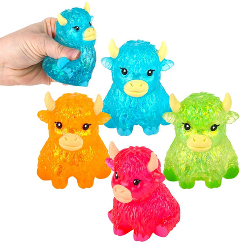 Four glitter squishy highland cow toys in blue, orange, pink, and green with hand demonstrating squeeze.