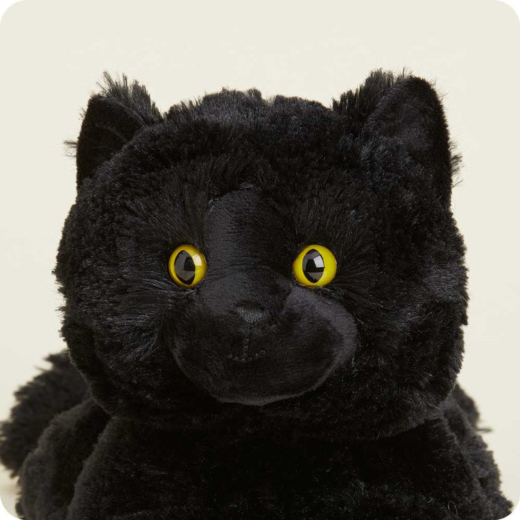 Warmies black cat stuffed animal plush with bright yellow cat eyes on neutral background