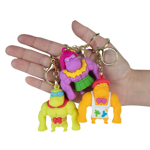 Hand holding three colorful Funkee Monkee Charmlets keychain figures on gold rings