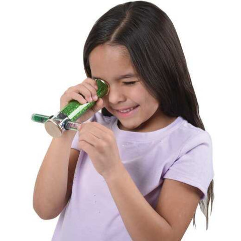 Young girl holding and looking through a green glitter wand kaleidoscope toy