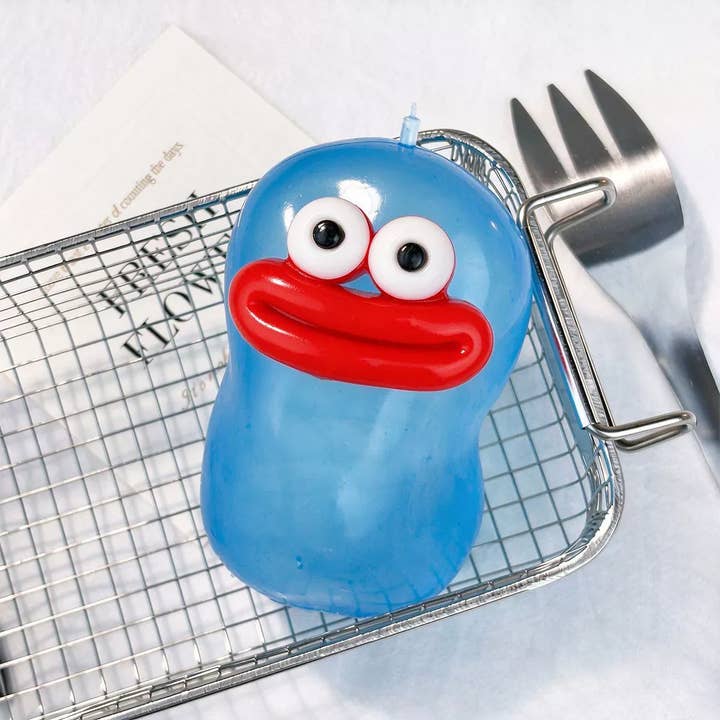 Blue goofy face squishy stress ball with googly eyes and red lips on metal rack