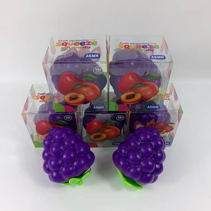 Purple grape-shaped squishy squeeze toys displayed with their clear packaging boxes featuring ASMR branding