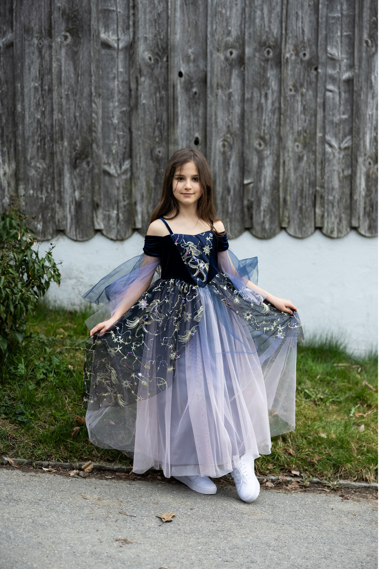 Child wearing navy blue twilight enchantress ball gown with gold star embroidery and tulle overlay
