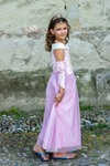 Young girl wearing pink velvety princess gown with tiara and arm warmers outdoors