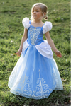 Young girl wearing light blue Cinderella princess dress with white puff sleeves and silver embroidery outdoors