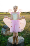 Young girl wearing pink and gold sequin butterfly fairy dress with wings and cowboy boots