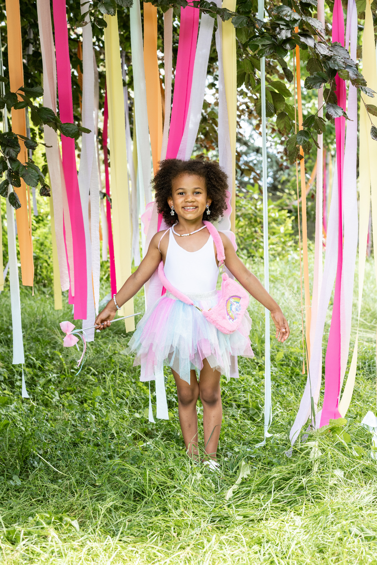 Young girl wearing mint pink tutu skirt with fairy wings and wand outdoors