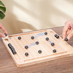 Two players using magnetic steel balls on a wooden grid board game set