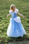 Young girl wearing light blue Cinderella princess dress with white puff sleeves and decorative swirl embroidery outdoors