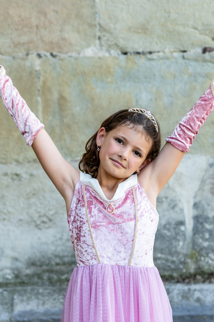 Child wearing pink velvet Sleeping Beauty princess gown with matching arm warmers and tiara