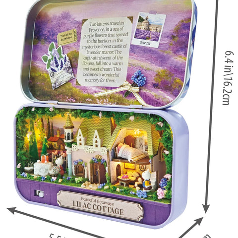 DIY miniature Lilac Cottage kit displayed open in purple tin box with illuminated castle scene
