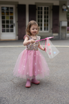 Young girl wearing pink sequin tulle dress with star pattern holding a fairy wand