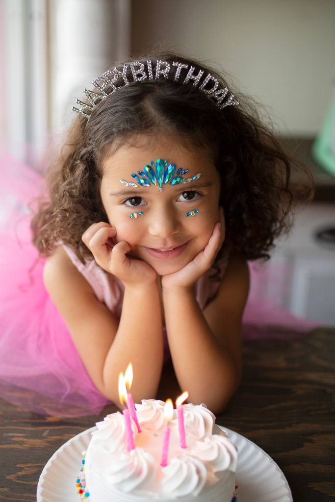 Young girl wearing Happy Birthday tiara with blue mermaid face crystal gems applied to forehead