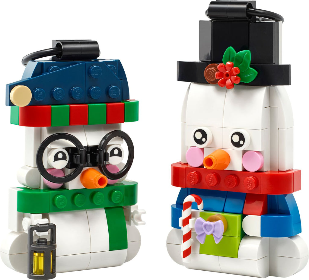 Two LEGO snowman ornaments with top hats, scarves, carrot noses, and holiday accessories on white background.