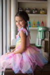 Young girl wearing rainbow sequin fairy dress with tulle skirt and blue fairy wings