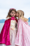 Child wearing a deluxe light pink velvet princess cape with lace trim outdoors near water