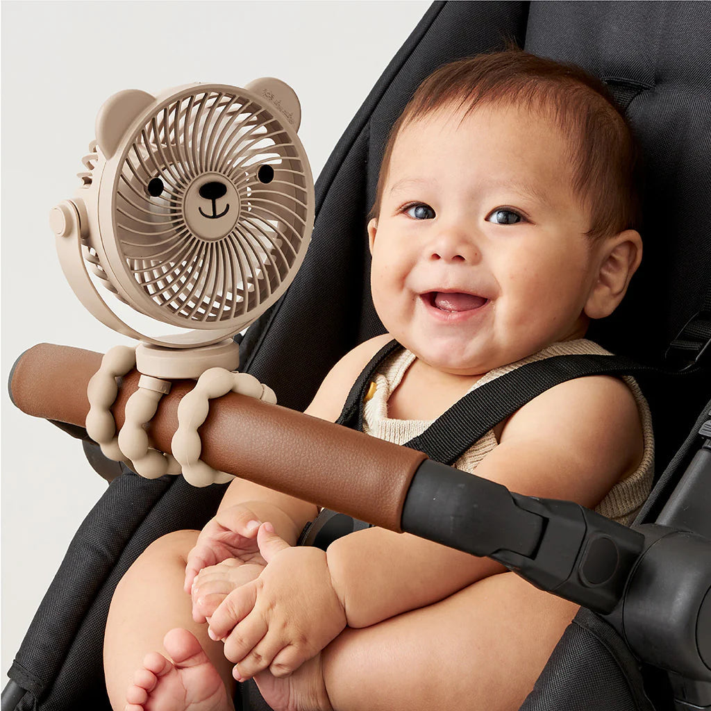 Smiling baby in stroller with bear-shaped Itzy Breeze clip-on fan attached to handlebar