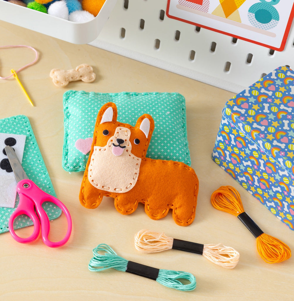 Mini craft kit featuring a handmade felt corgi dog on a teal pillow with embroidery thread and scissors