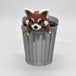 3D printed red panda figure draped over a miniature gray trash can toy