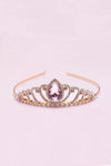 Rose gold tiara headband with pink teardrop gemstone and rhinestone embellishments on pink background