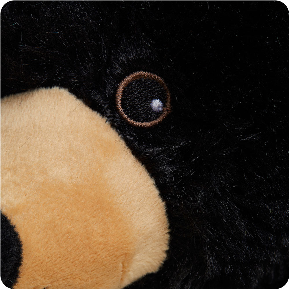 Close-up of black bear stuffed animal face showing embroidered eye and tan muzzle