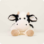 Warmies laying down cow stuffed animal with black and white plush and tan hooves