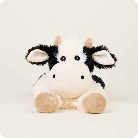 Warmies laying down cow stuffed animal with black and white spots and tan hooves
