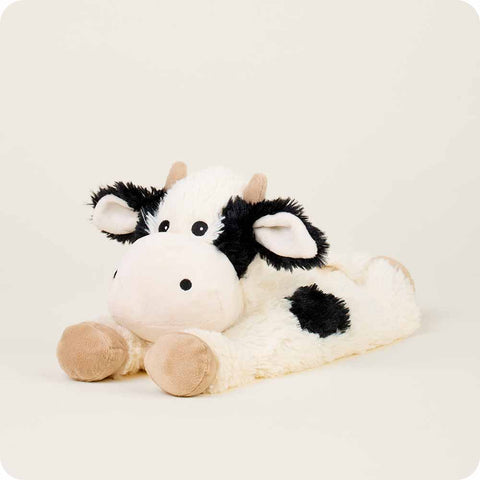 Warmies laying down cow stuffed animal with black and white spots and tan hooves