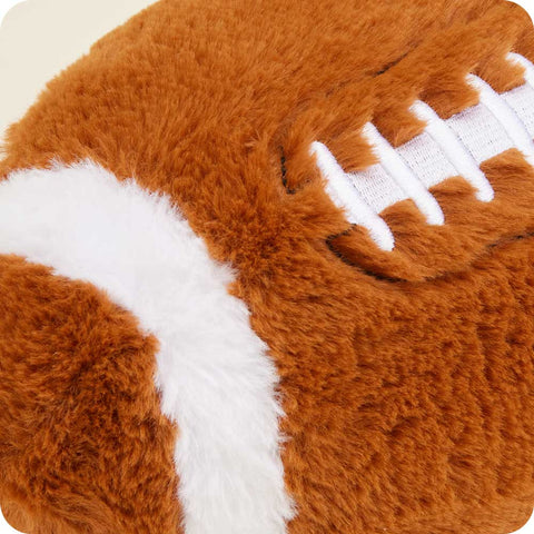 Warmies plush football stuffed animal with white laces on cream background