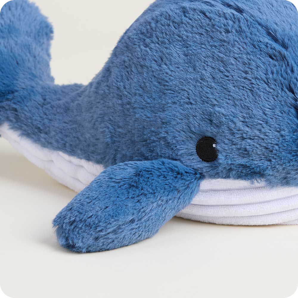 Close-up of a blue plush whale stuffed animal with white belly and black embroidered eye