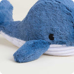 Close-up of a blue plush whale stuffed animal with white belly and black embroidered eye