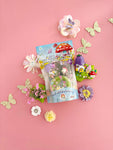 Fairy Garden Mini KidDough Play Pack on pink background surrounded by decorative flowers and glitter butterflies