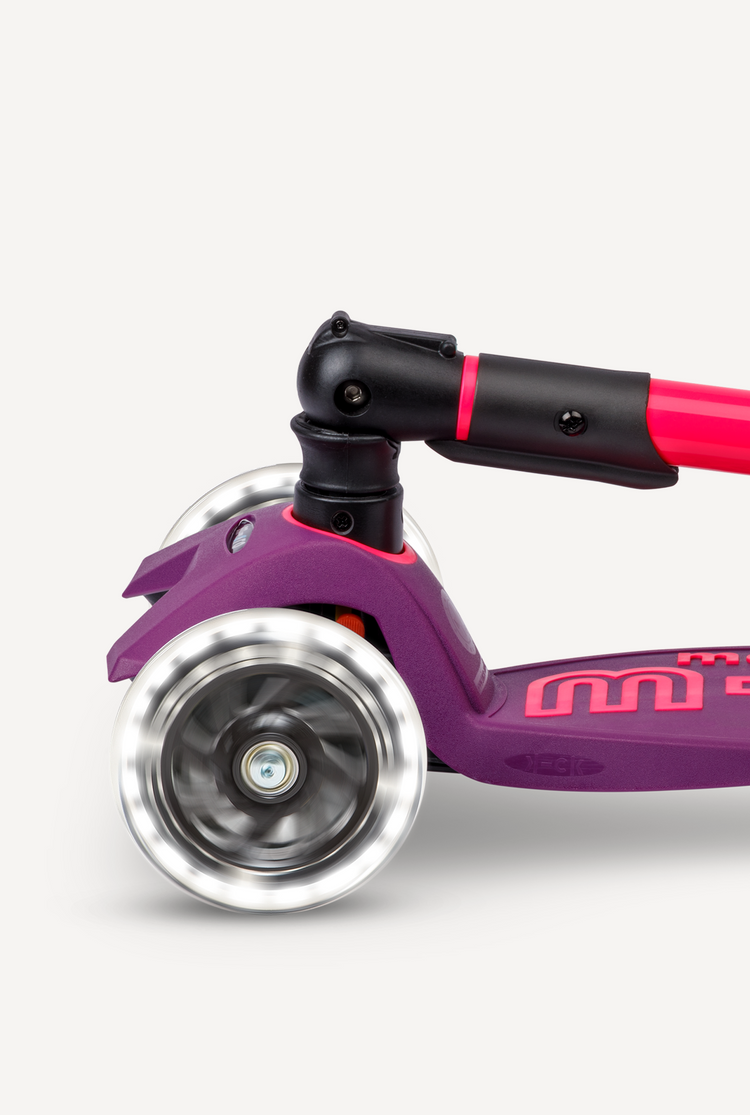 Close-up of Micro Maxi Foldable LED scooter front wheel in neon pink and purple on white background