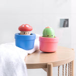 Cute kawaii wooden bath toy mushroom in blue pot beside green cactus in pink pot