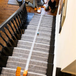 Two children playing with Air Toobz tube toy set running down carpeted staircase at home.