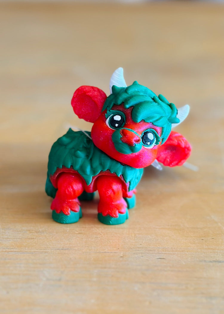 Holly Jolly Micro Moos red and green dragon-like miniature toy figurine on wooden surface