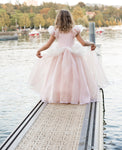 Young girl wearing a light pink princess ball gown on a waterfront dock
