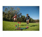 Two children jumping outdoors playing with Dueling Stomp Rocket toy on green grass