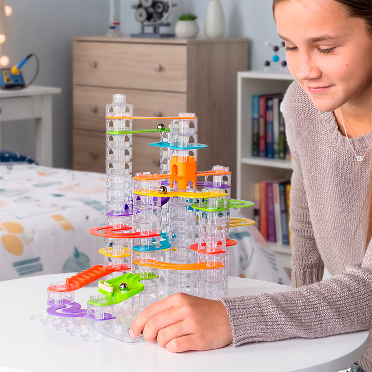 Girl smiling while playing with colorful Trestle Track Pro marble run set on table