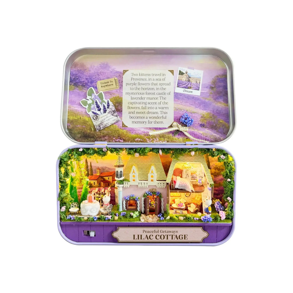 DIY miniature Lilac Cottage kit displayed open in purple tin box with illuminated castle scene