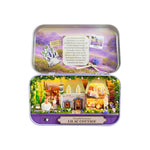 DIY miniature Lilac Cottage kit displayed open in purple tin box with illuminated castle scene