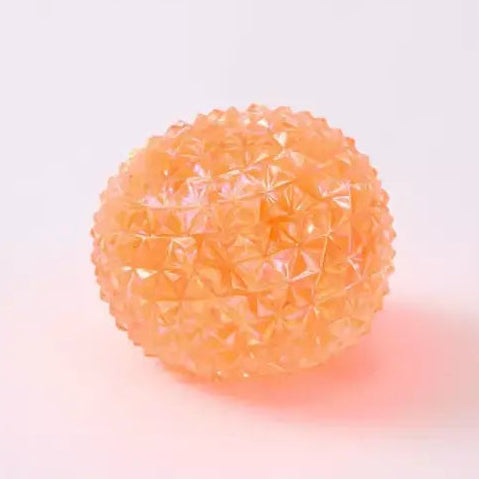 Orange translucent spiky squishy orb toy with faceted crystal-like texture on white background
