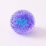Purple iridescent spiky squishy orb toy with faceted crystal-like texture on white background.